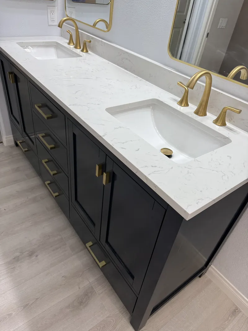 Close view of the new vanity top with two undermount sinks, brushed gold widespread faucets and gold drawer pulls