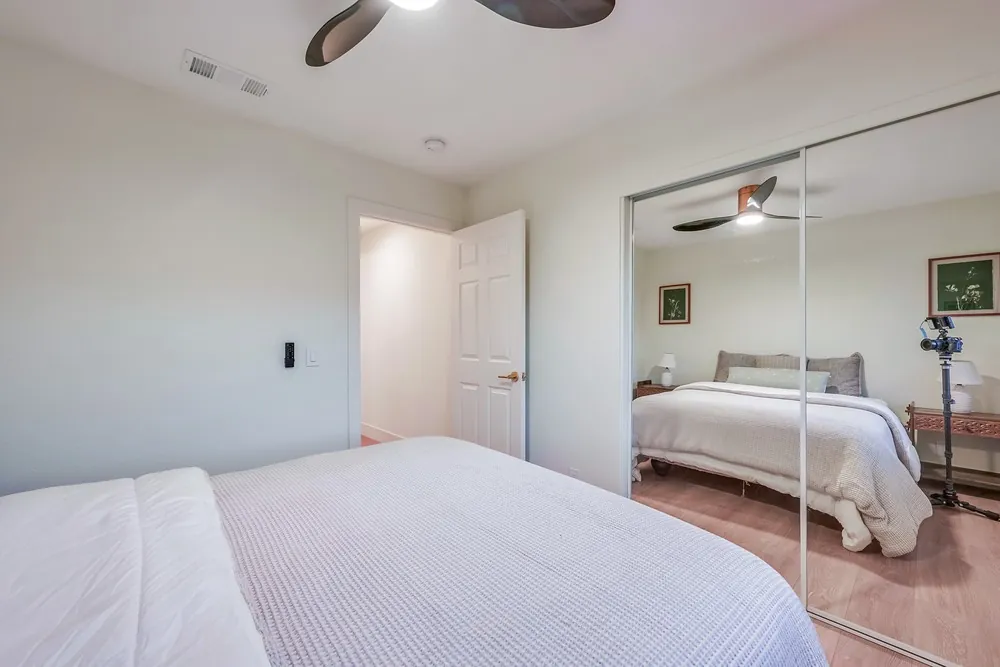 Guest bedroom with new plank flooring, ceiling fan and mirrored closet doors
