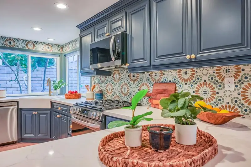 Navy raised-panel kitchen with brass-tone hardware, apron-front sink, patterned tile backsplash and white counters