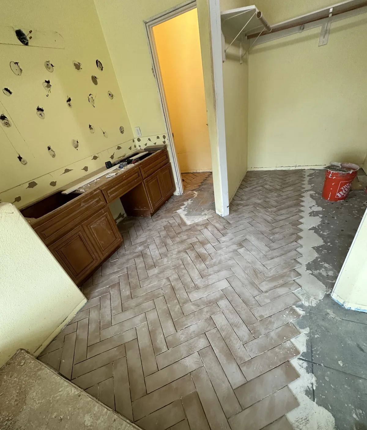 New herringbone floor tile going down in the primary bathroom with the old vanity and patched walls still in place