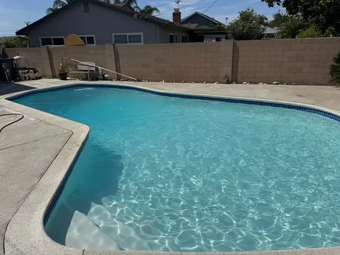 Finished pool with fresh plaster and turquoise water, entry steps in the foreground and a block wall behind