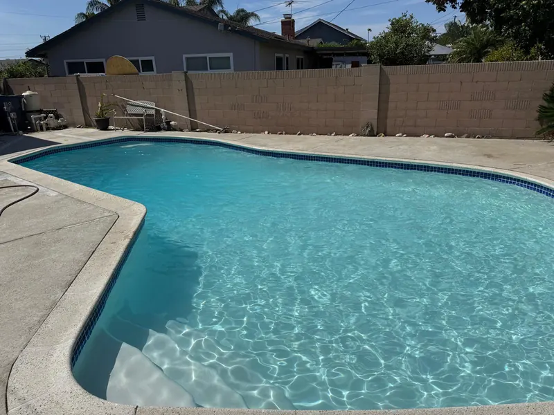 Finished pool with fresh plaster and turquoise water, entry steps in the foreground and a block wall behind