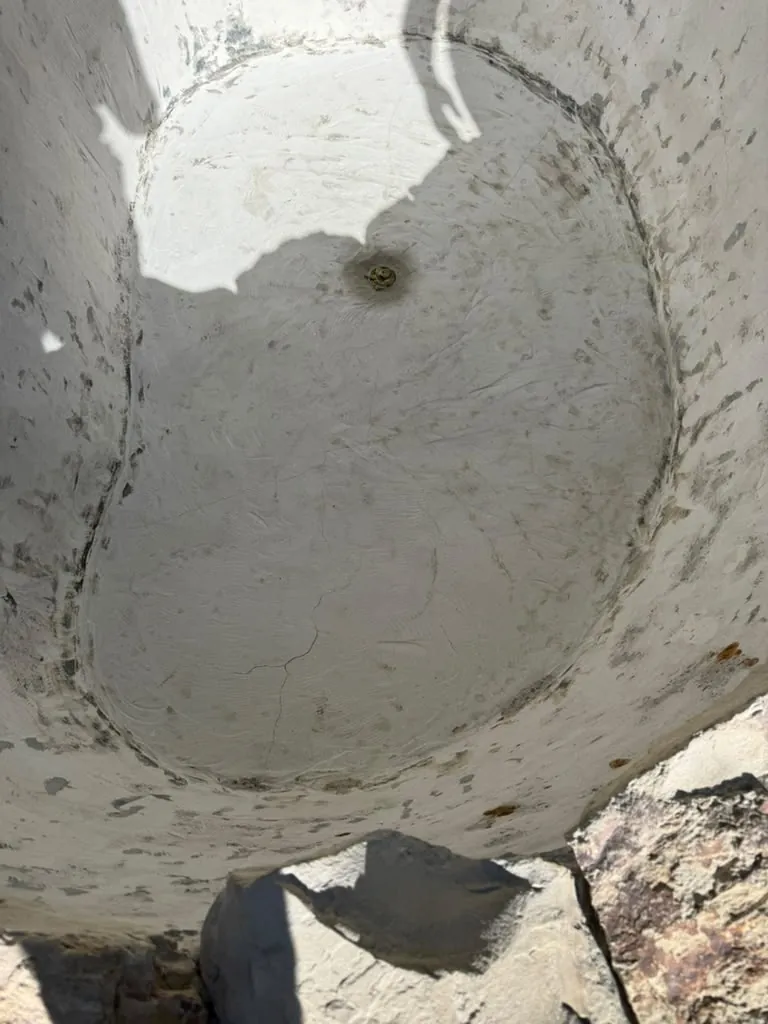 Drained fountain basin with the old plaster stained and worn around the drain, seen from above