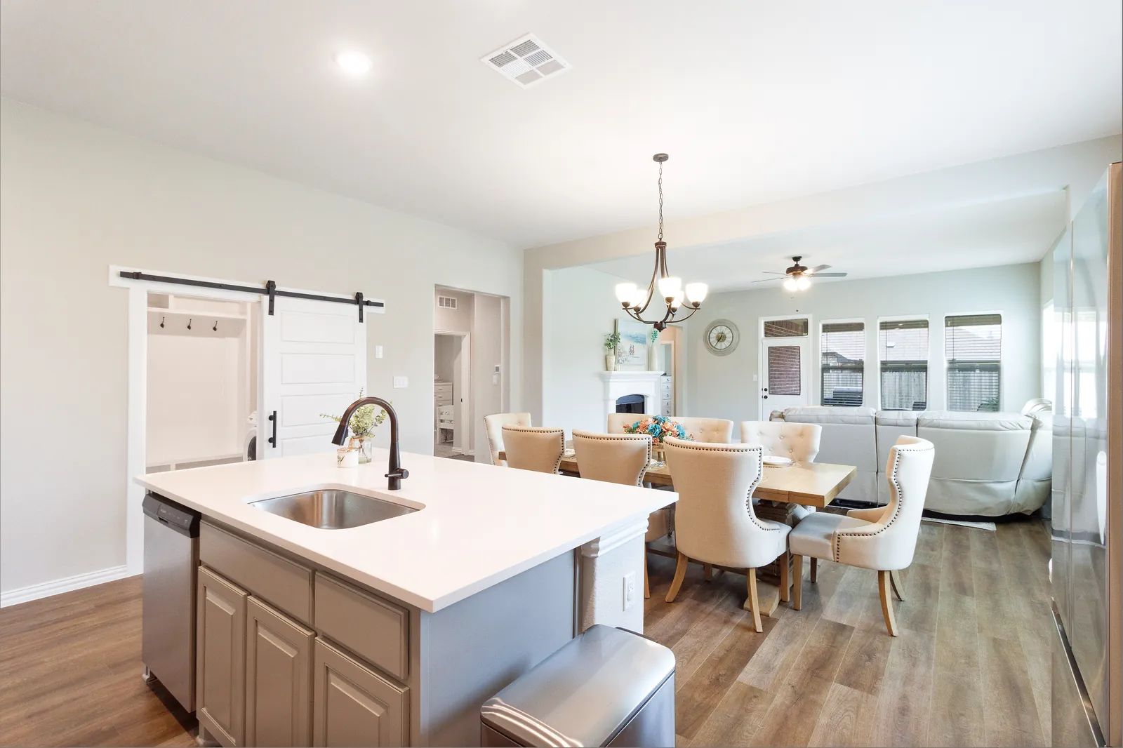 Kitchen island with an undermount sink and dishwasher under a quartz top, open to the dining room past a sliding barn door
